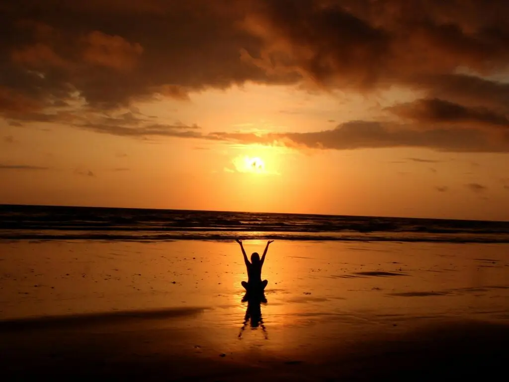 Peaceful meditation silhouette at sunset on a serene beach.