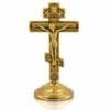 Standkreuz aus Metall goldfarben mit Kruzifix und abnehmbarem Sockel Goldfarbenes Standkreuz aus Metall mit gegossenem Christus-Korpus, roten Schmucksteinen und rundem abnehmbarem Zierfuß