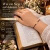 Hand mit Tiny Cross Armband aus Gold 585 und weinrotem Band auf einer aufgeschlagenen Bibel