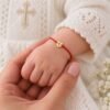 Rotes Taufarmband mit Goldherz 585 am Handgelenk eines Babys