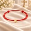 Taufarmband mit Goldherz und rotem Band auf rotem Satin als Geschenkidee zur Taufe und Geburt